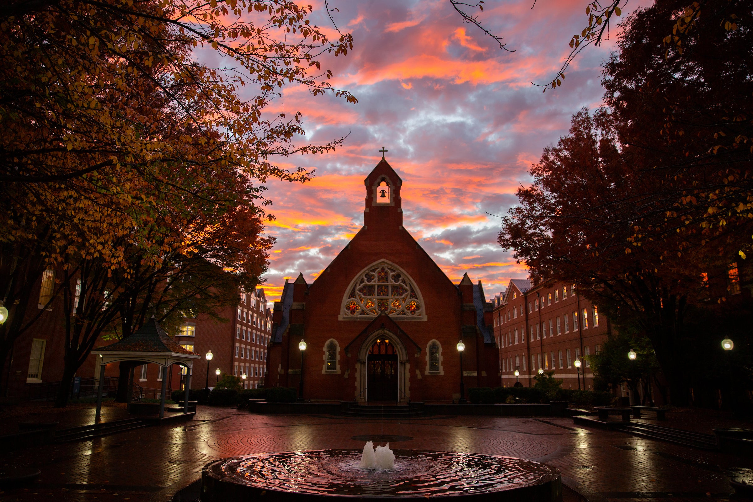 A fountain bubbles in front of Dahlgren Chapel during sunset.