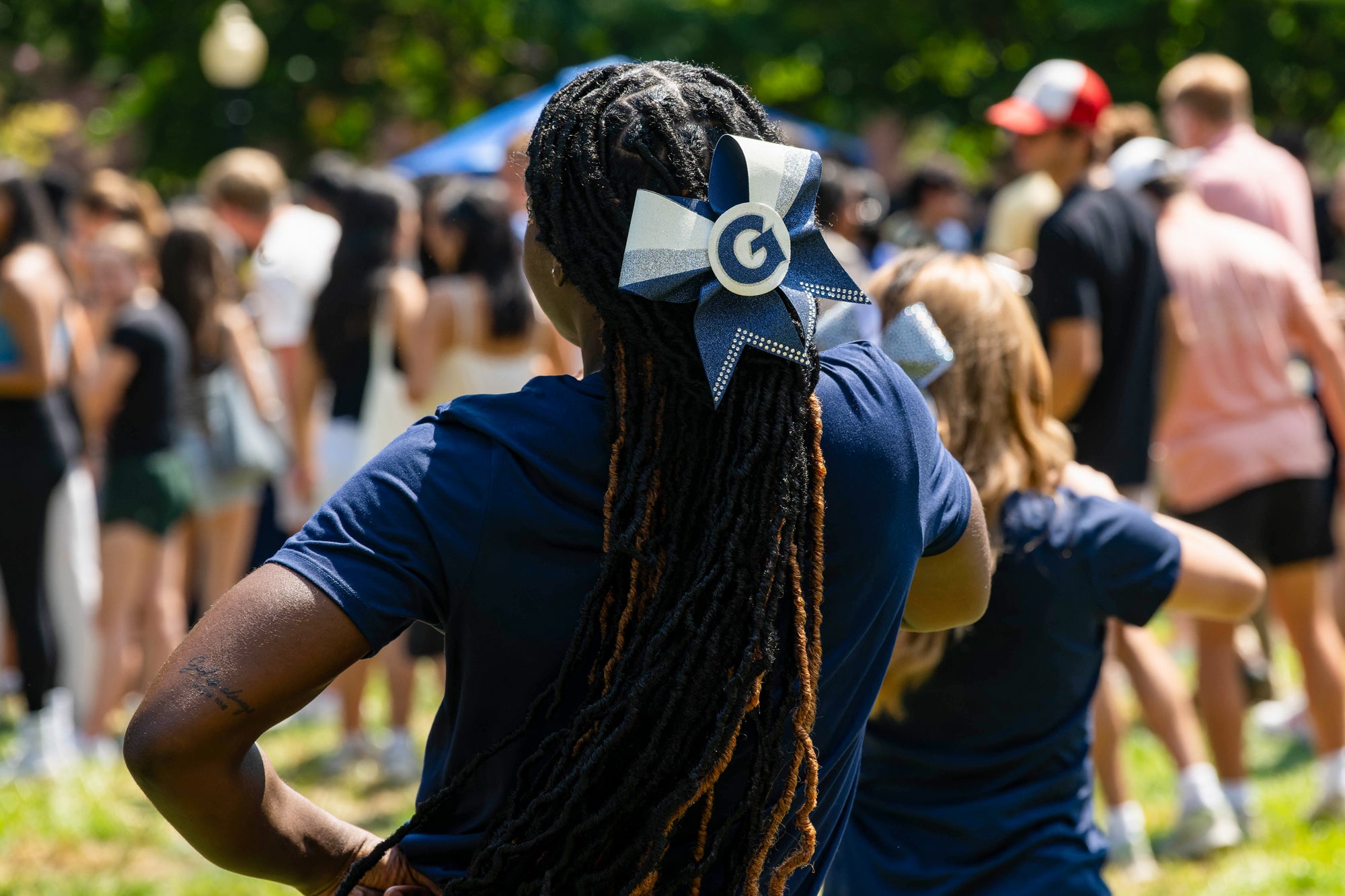 The back of a Georgetown cheerleader, who is wearing a bow in her hair with a Georgetown logo on it.