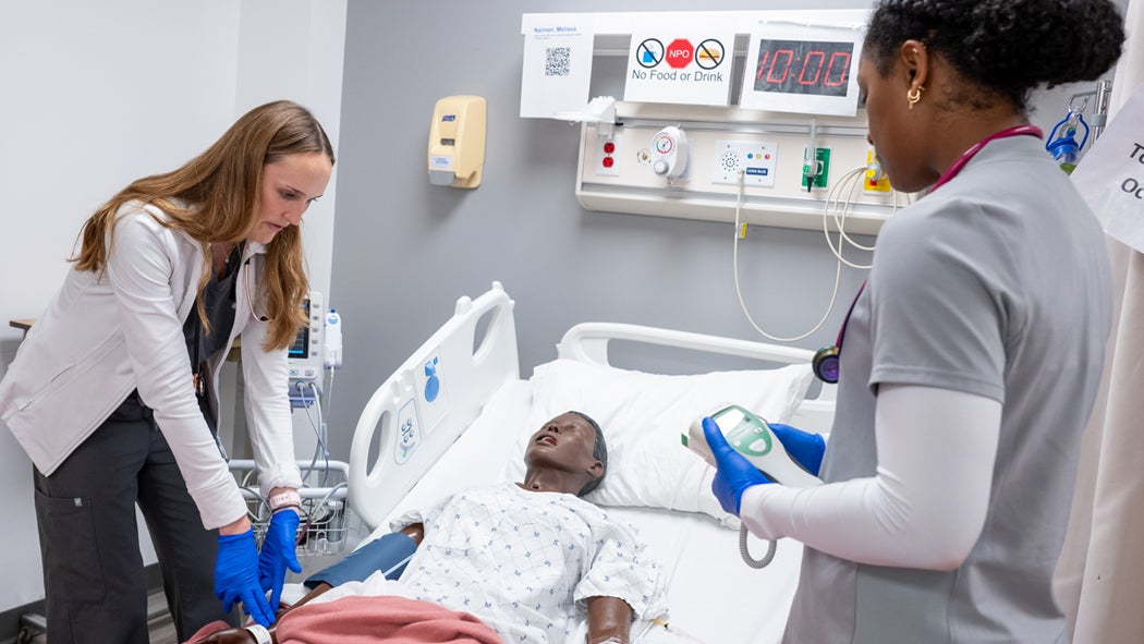 Two students examine a human-like simulator in the O’Neill Family Foundation Clinical Simulation Center.
