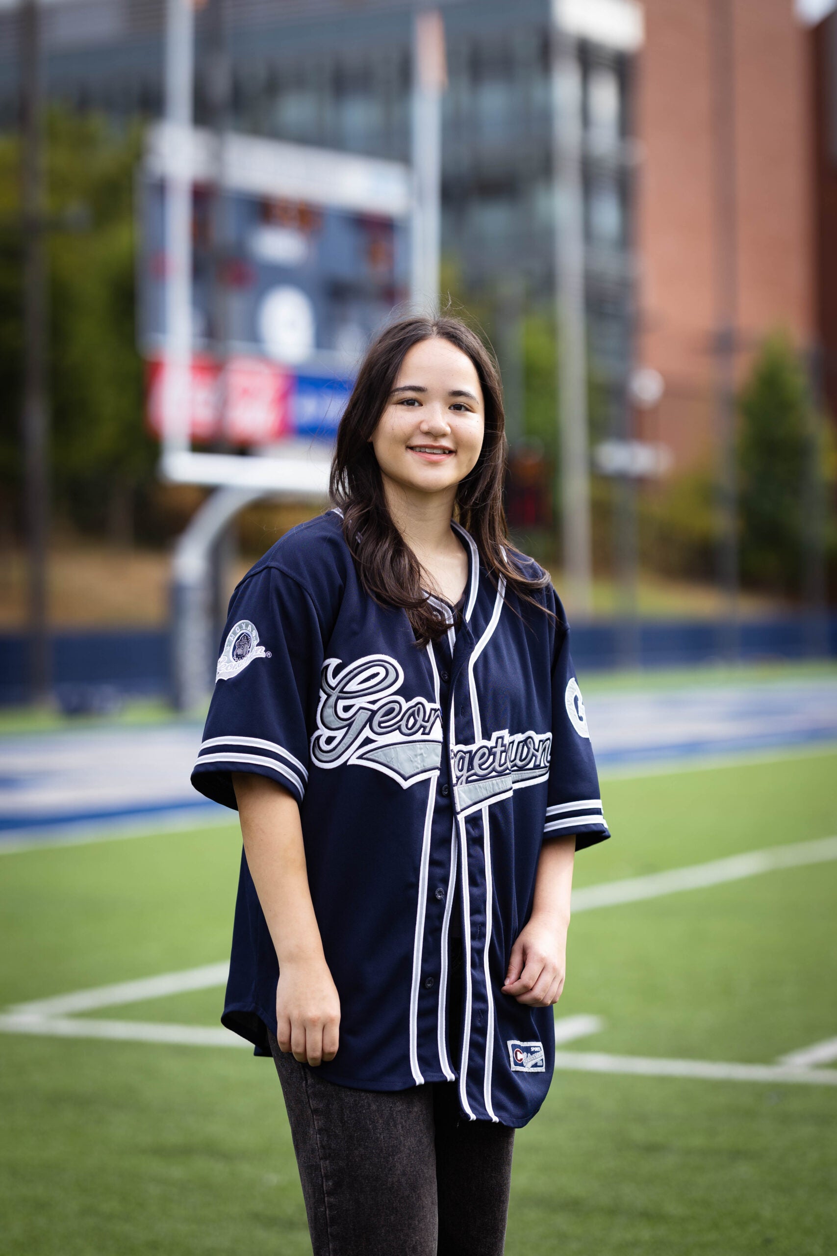 Juliette stands on Cooper Field while wearing a Georgetown baseball jersey.