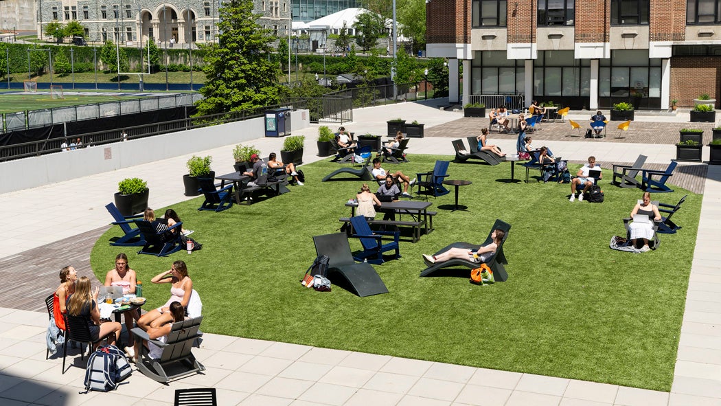 Students enjoying a sunny day in chairs spread across the Harbin Patio.