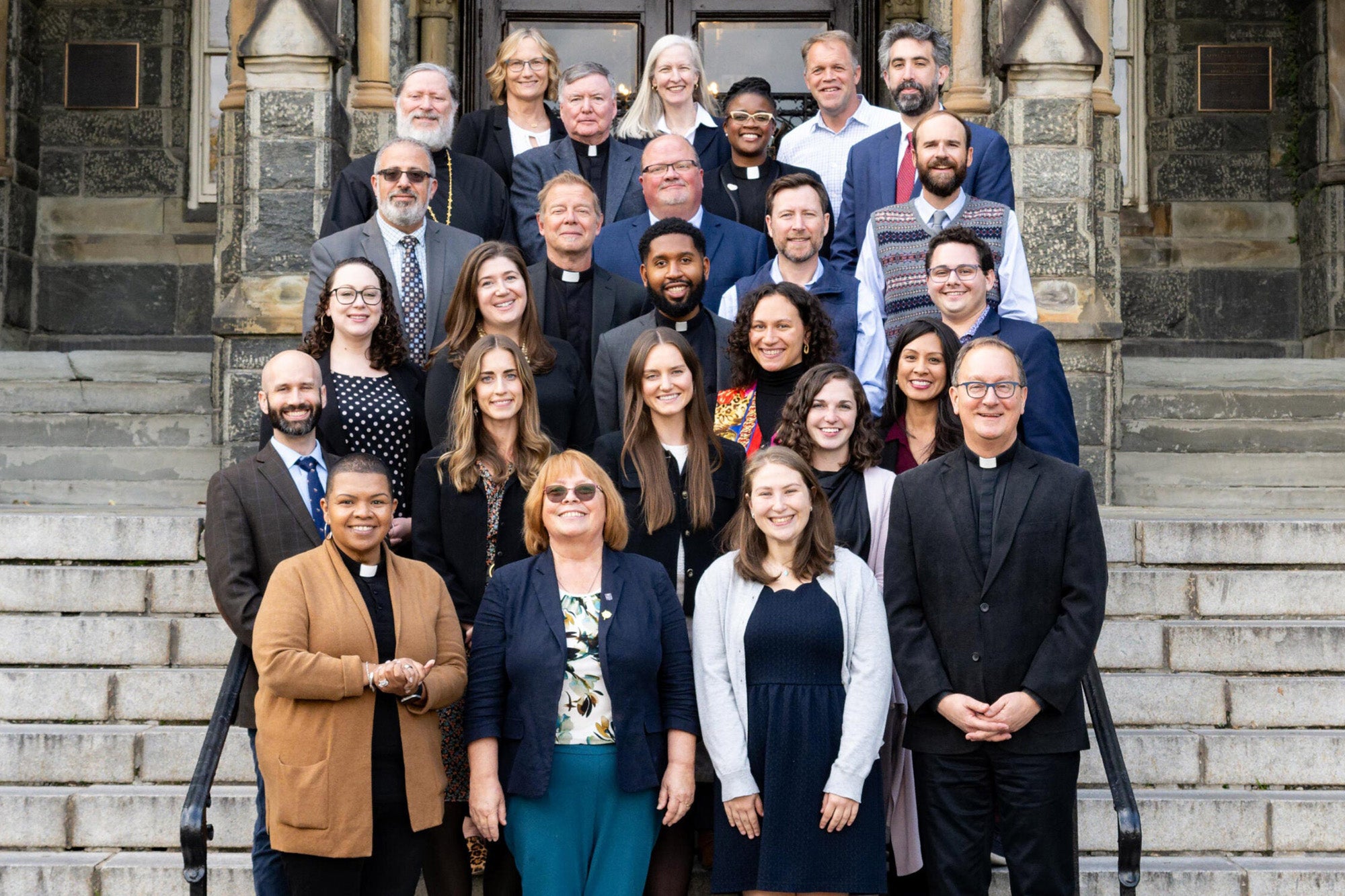 Georgetown's Campus Ministry team stands on the front steps of Healy Hall.
